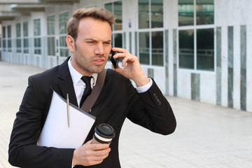 Annoyed businessman on the phone outside office building 