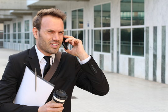 Annoyed businessman on the phone outside office building