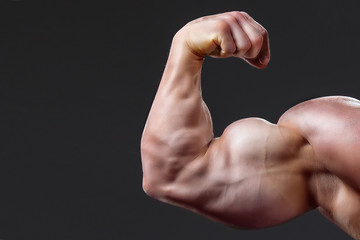 bodybuilding naked male arm with biceps on grey background - obrazy, fototapety, plakaty