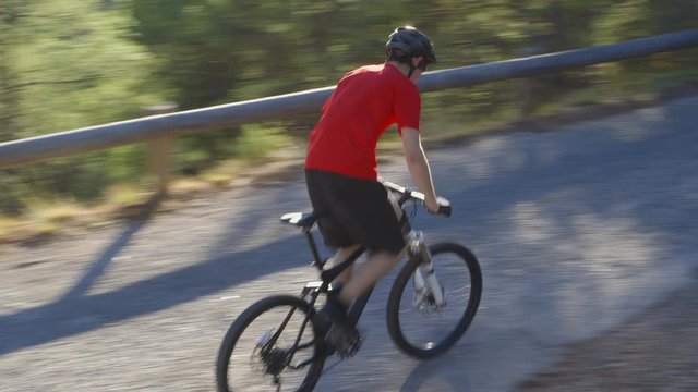 Mountain Biking - High-angle shot of an athletic guy on a mountain bike who is driving uphill respectively downhill on a beautiful secondary road - ProRes