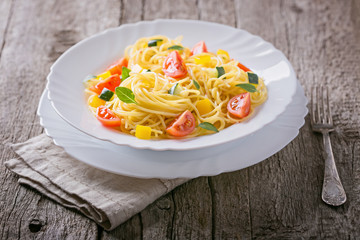 Pasta with zucchini, tomatoes, sweet pepper and basil leaves