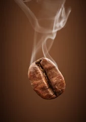 Foto op Plexiglas Closeup falling coffee bean with smoke on brown background © dimj