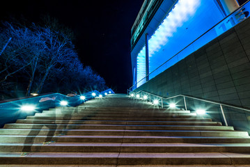 Mann geht bei Nacht in München eine beleuchtete Treppe hoch