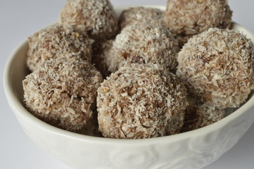 Homemade cookies - millet flake balls in grated coconut in white bowl