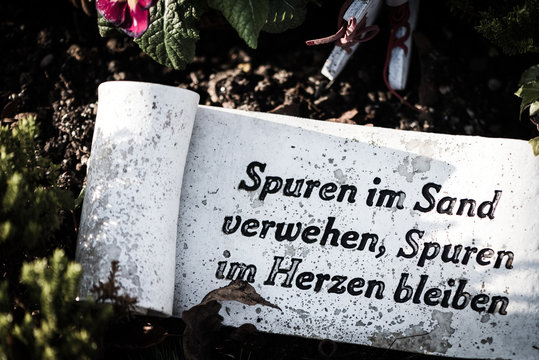 Steinplatte auf einem Grab "Spuren im Sand verwehen, Spuren im Herzen bleiben"