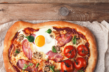 Fresh delicious pizza from the oven with egg, prosciutto and tomato