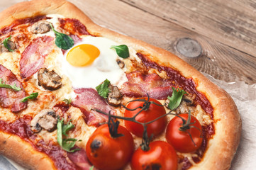 Fresh delicious pizza from the oven with egg, prosciutto and tomato