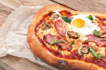 Fresh delicious pizza from the oven with egg, prosciutto and tomato