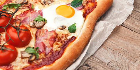 Fresh delicious pizza from the oven with egg, prosciutto and tomato
