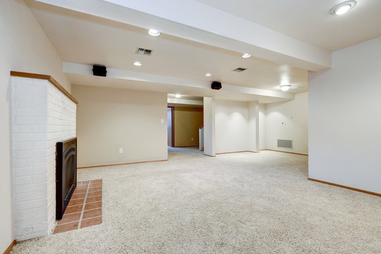 White empty basement room with fireplace