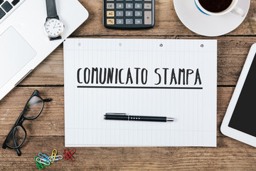 Comunicato stampa, Italian text for Press Release on note pad at office desk with computer technology, high angle