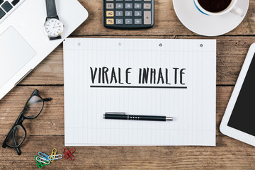 Virale Inhalte, German text for Viral Content on note pad at office desk with computer technology, high angle