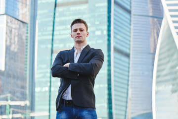 The man in the jacket on the background of skyscrapers with glass facade