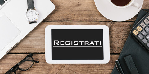 Registrati, Italian text for Register on screen of tablet computer at office desk