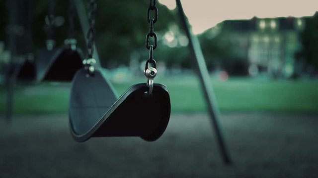 Empty swing in park during evening hours with no children.
