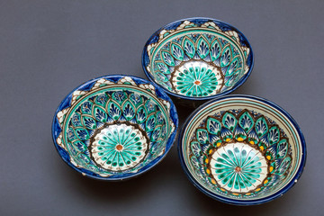 Ethnic Uzbek ceramic tableware on the gray background. Decorative ceramic cups with traditional uzbekistan ornament.