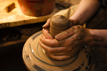 Women hands. Potter at work. Creating dishes. Potter's wheel. Dirty hands in the clay and the potter's wheel with the product.
