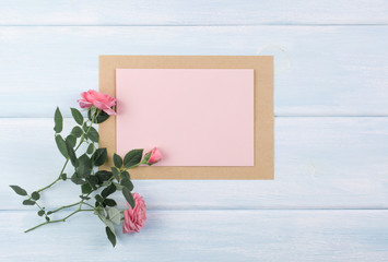 Wooden background with roses and empty paper with place for text