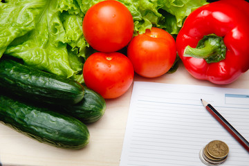 Fresh vegetables on the table: red pepper, lettuce, cucumber, tomatoes, sheet for notes - notepad. Cutting board, Food imitation. Inflation