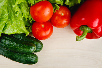 Fresh vegetables on the table: red pepper, lettuce, cucumber, tomatoes. Cutting board