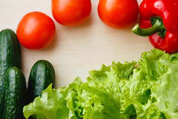 Fresh vegetables on the table: red pepper, lettuce, cucumber, tomatoes. Cutting board