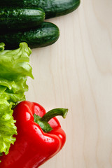 Fresh vegetables on the table: red pepper, lettuce, cucumber. Cutting board