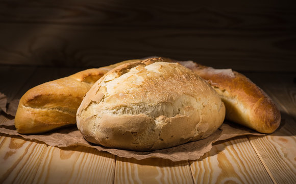 Assortment of baked bread on wooden table background