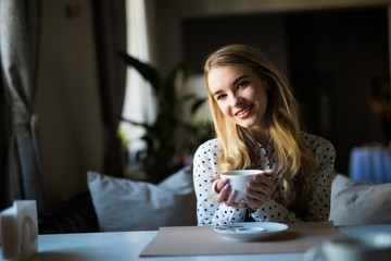 pretty young woman sitting in the cafe with a cup of or coffee