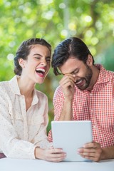 Couple laughing while using digital tablet