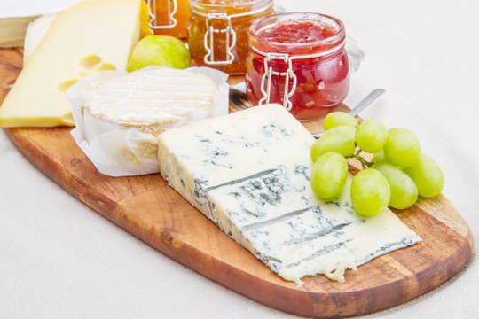 wooden cutting board with cheese and jams
