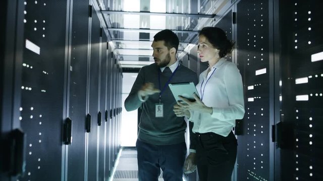 Male and Female Server Technicians Working in Data Center. Running Rack Server Diagnostics. Woman Uses Tablet Computer. Shot on RED EPIC-W 8K Helium Cinema Camera.