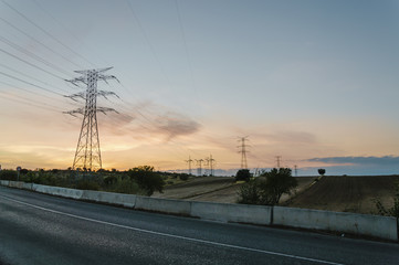 Fototapeta na wymiar Road against high voltage towers at sunset