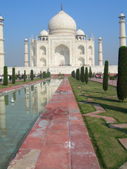Obraz premium Side perspective of the Taj Mahal mausoleum in Agra, India, with the main building dome framed by the minaret towers and the reflection pool.