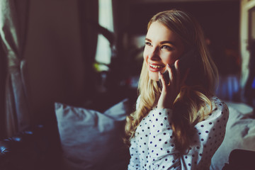 Young woman talking on mobile phone and drinking coffee at the table in cafe