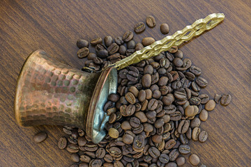 Copper coffee pot and coffee seeds on wood