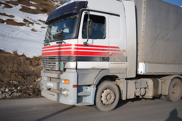 White refrigerated truck on winter road on background of the mountains