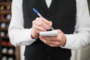 Male waiter taking down order in the restaurant
