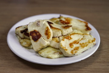 Grilled halloumi cheese on the plate. On the wooden table.