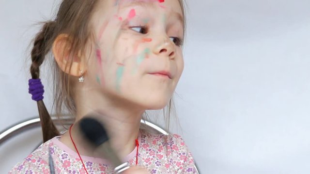 Little girl paints her face