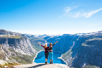 Happy people relax in cliff during trip Norway. Trolltunga hiking route - obrazy, fototapety, plakaty