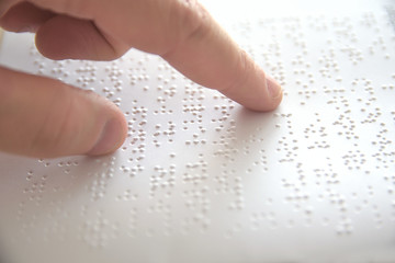 Hand of a blind person reading some braille text touching the relief. Empty copy space for Editor's content. - obrazy, fototapety, plakaty