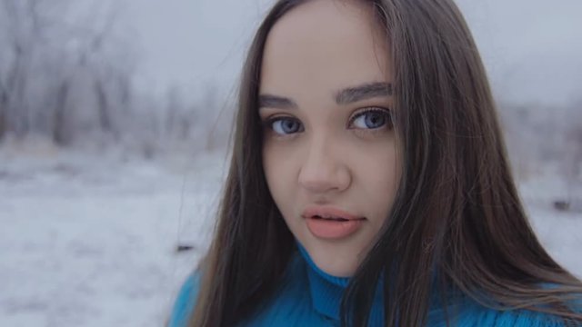 Beautiful cute girl with long hair posing in the winter forest.