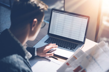 Closeup view of banking finance analyst in eyeglasses working at sunny office on laptop while...