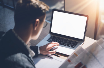 Closeup view of banking finance analyst in eyeglasses working at sunny office on laptop while sitting at wooden table.Businessman analyze stock report on notebook screen.Blurred,horizontal mockup.