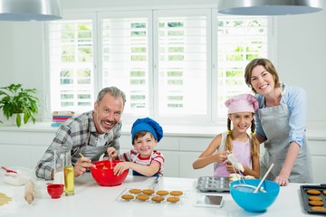 Smiling parents and kids preparing cookies in kitchen