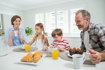 Obraz na płótnie Canvas Smiling family having breakfast in the kitchen