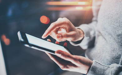 Female finger pointing on screen smartphone on background illumination glow bokeh light in night atmospheric.Horizontal, blurred background, flares.