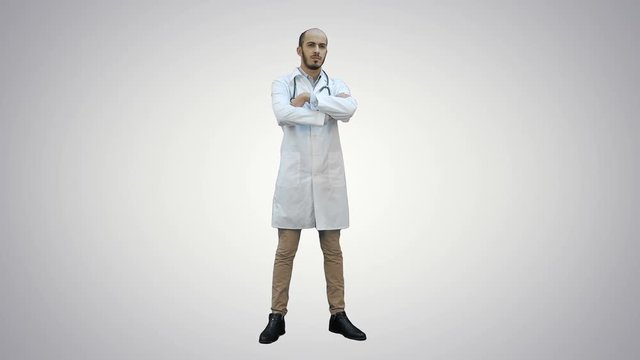 Serious medical worker standing and folding his arms on his chest on white background.