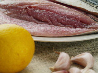 Uncooked fillets of mackerel lemon and garlic cloves.