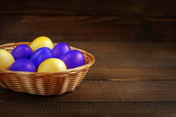 Yellow and purple Easter eggs in the basket. The concept of a holiday and a happy Easter